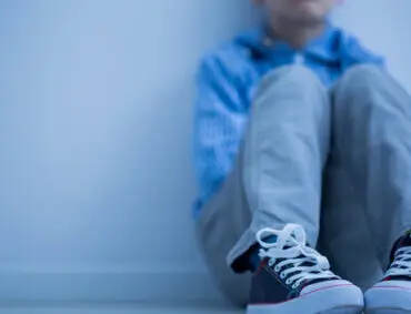 A child is sitting on the floor. Get counseling services for childhood anxiety.