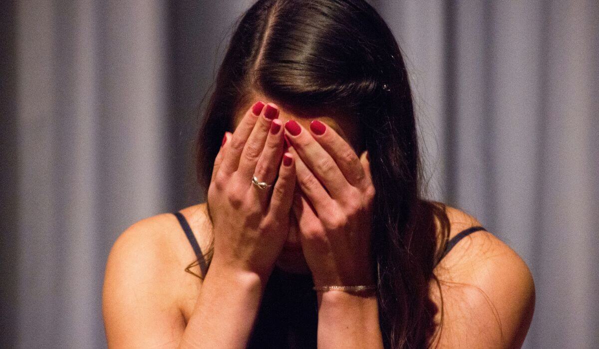 A woman with her face in her hands, experiencing deep grief, representing the stages of grief.