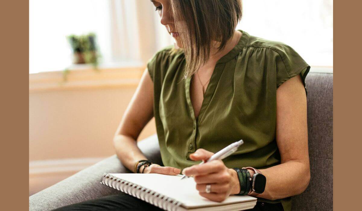 A woman sitting with a notepad, thoughtfully writing, representing the process of choosing based on a Therapist’s Qualifications and certifications.