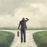 A man standing at a crossroads, symbolizing decision-making and coping with change during life transitions. The foggy background represents uncertainty, while the two paths signify different choices ahead.