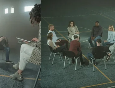 A group therapy session with diverse LGBTQ+ individuals sitting in a circle, led by a therapist. The participants appear engaged in a supportive discussion, highlighting the importance of trauma-informed counseling for LGBTQ+ clients.