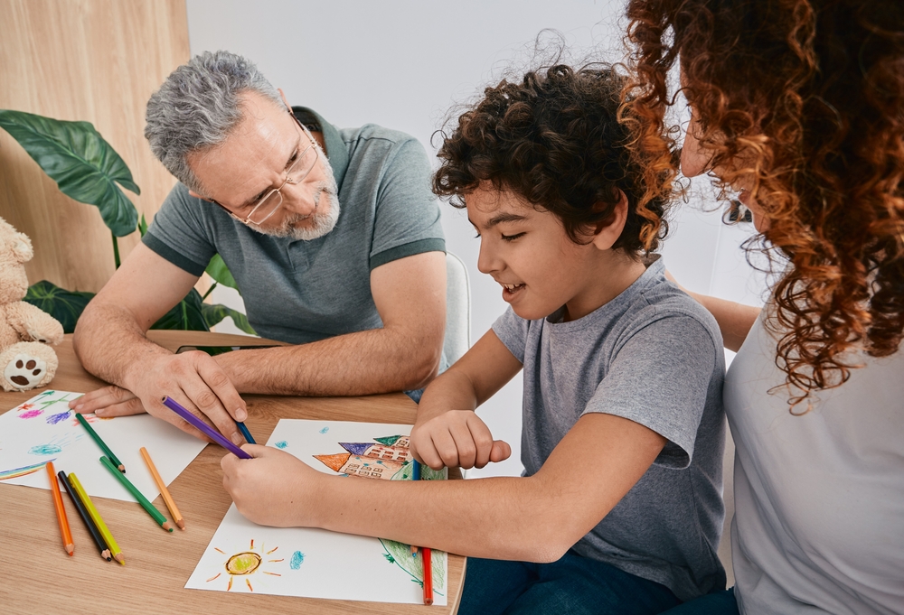 A family engages in drawing together at a table, fostering creativity and connection during parent-child counseling