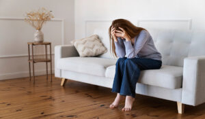 Stressed woman sitting on a couch, exploring effective strategies for managing anxiety in daily life.