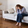 Stressed woman sitting on a couch, exploring effective strategies for managing anxiety in daily life.