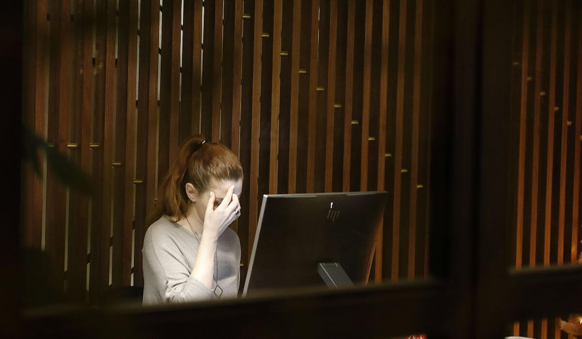 Overworked woman at a computer experiencing stress and anxiety, highlighting the impact of workplace pressure.