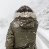 A person in a winter coat walking in snowfall, representing the importance of outdoor activities to manage Seasonal Affective Disorder (SAD).