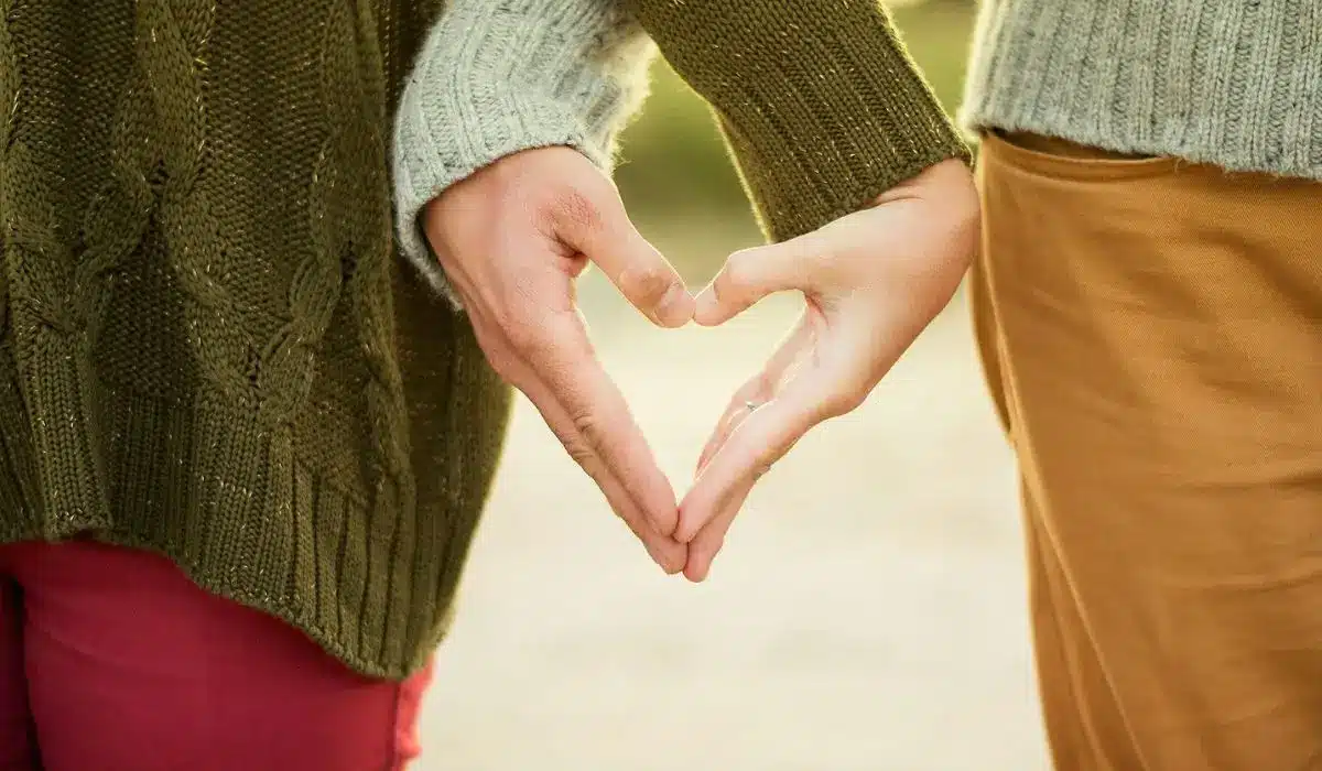 Couple forming a heart shape with their hands, symbolizing connection in couples counseling.