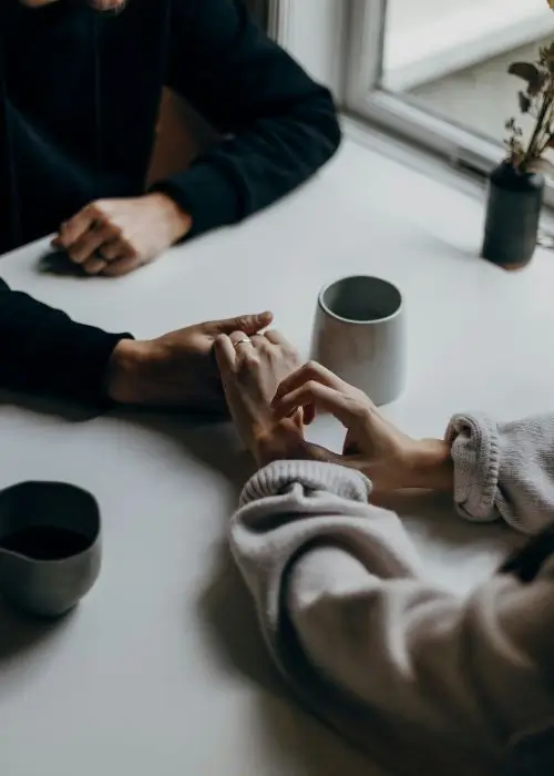 Couple holding hands across a table during a couples counseling session.