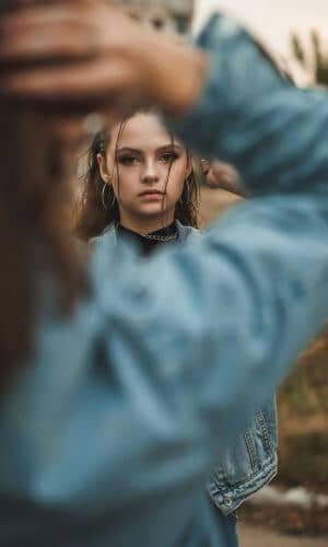 Teenage girl looking distant while someone stands in front of her, representing emotional disconnection and struggling with anxiety.