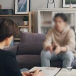 Teen in a counseling session with a therapist, seated across from each other, symbolizing therapy for struggling with anxiety.