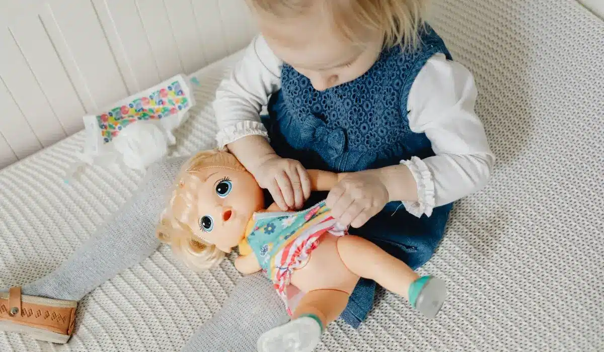 Child in play therapy session using doll play for emotional expression.