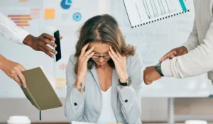 Professional woman overwhelmed at work needing stress management therapy support.