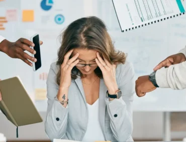 Professional woman overwhelmed at work needing stress management therapy support.