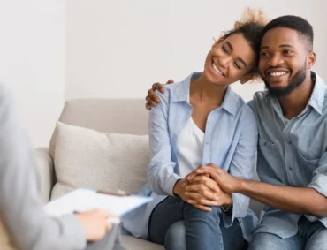 Smiling couple holding hands during supportive couples counseling session focused on building connection and emotional trust.