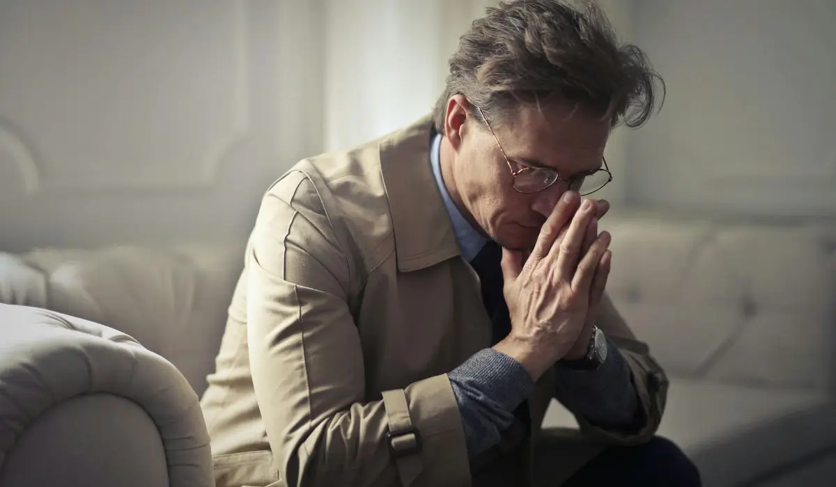 Middle-aged man in professional clothing sitting with head bowed, conveying stress and silent depression in executives.
