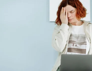 Tired woman with hand on face working at a laptop, illustrating silent depression in high-achieving professionals.