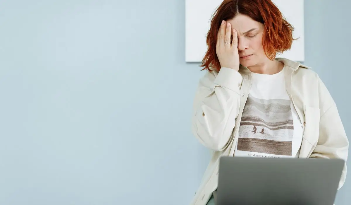Tired woman with hand on face working at a laptop, illustrating silent depression in high-achieving professionals.
