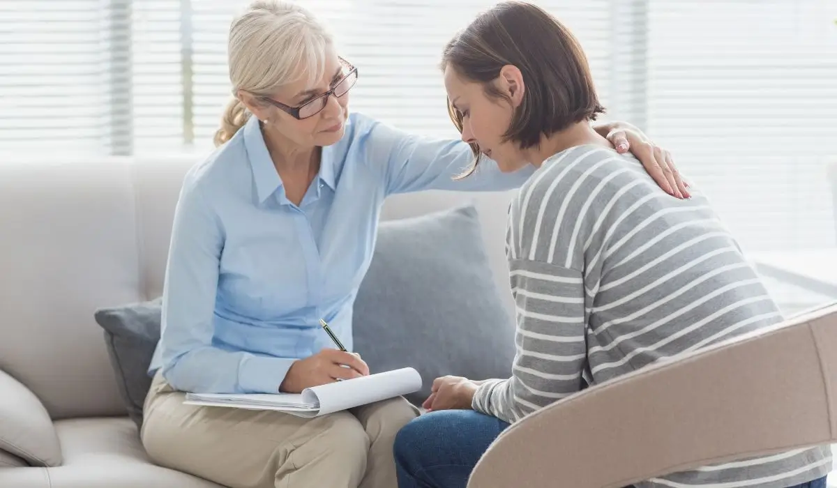 Therapist comforting client during PTSD symptoms treatment in a private counseling session focused on healing.