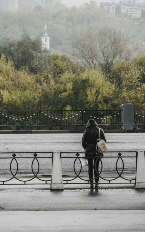 A person standing alone near a fence, contemplating in solitude, symbolizing coping with loss.